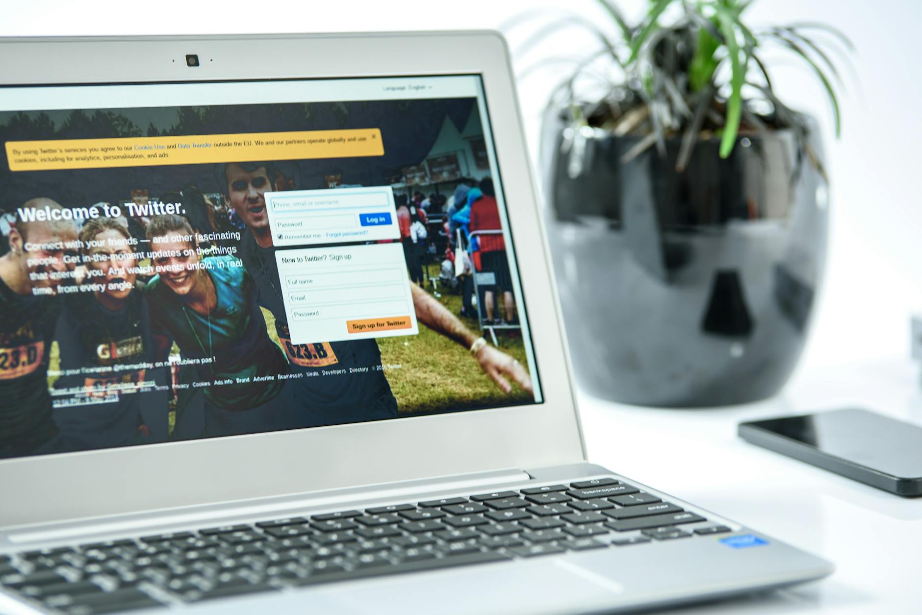 A laptop displaying the Twitter login page with a plant nearby