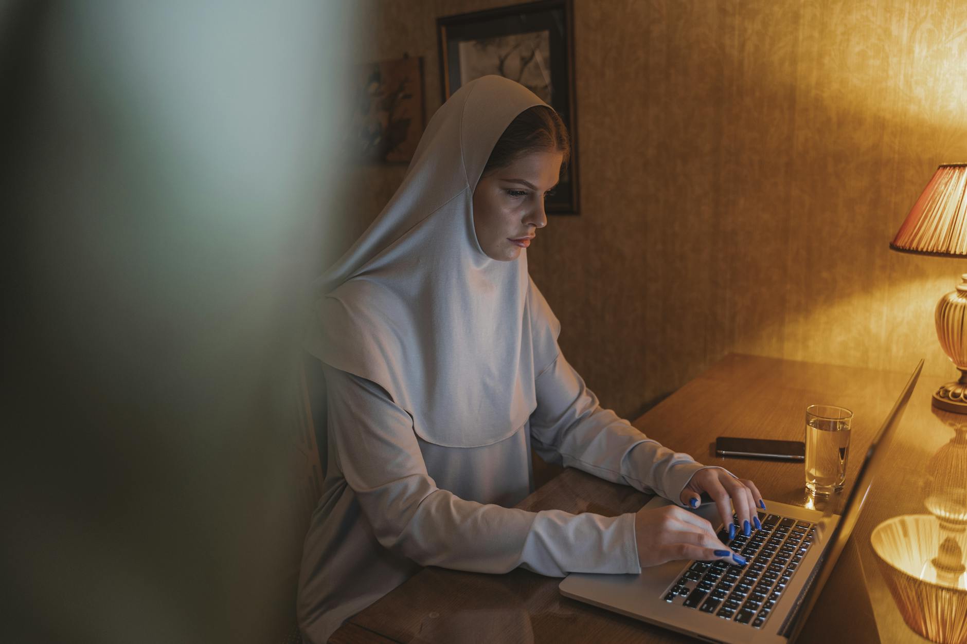A woman in a hijab working on a laptop at a desk