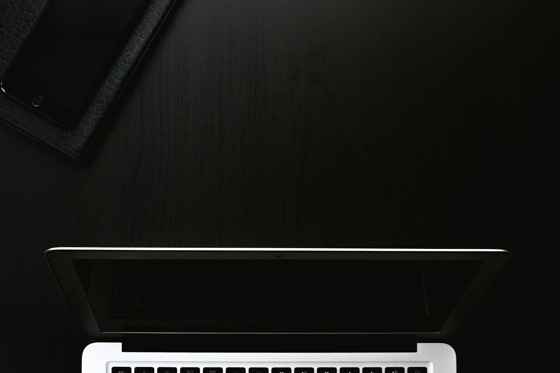 A laptop and smartphone on a dark wooden surface