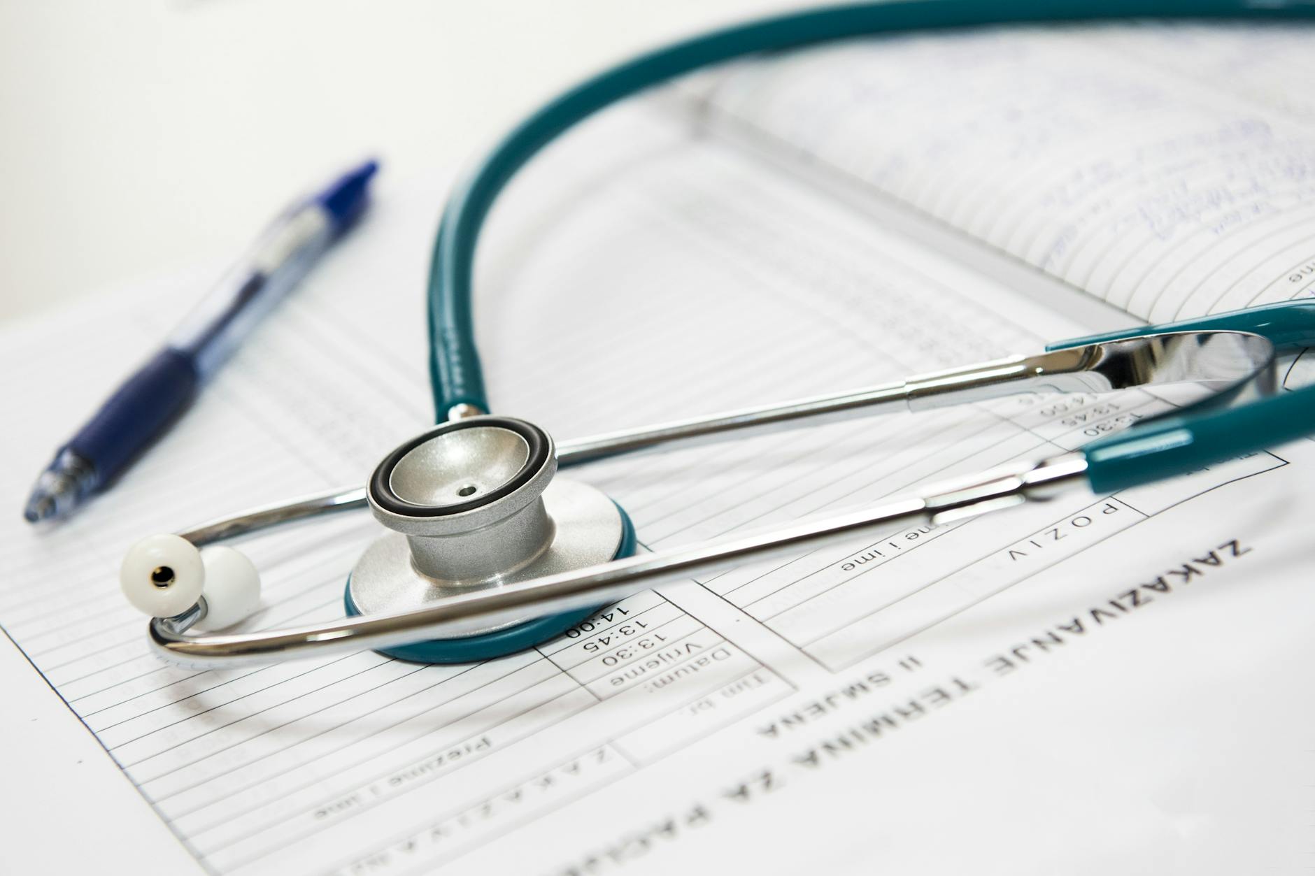 A stethoscope resting on a medical chart with a pen nearby