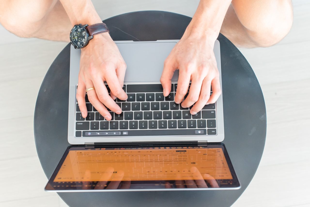 Hands typing on a laptop with a reflective screen