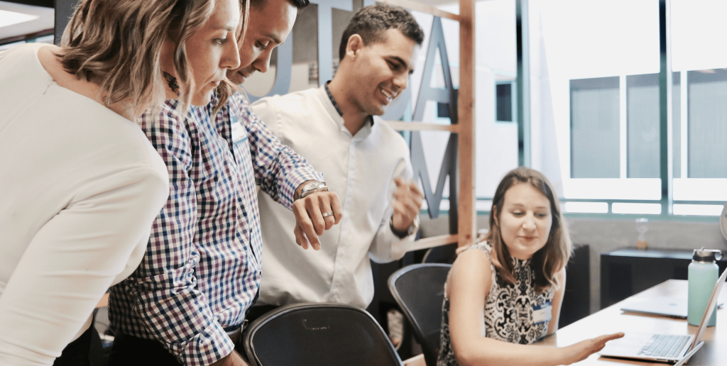 A group of people collaborating around a laptop in an office setting